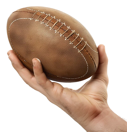 Une main tient un ballon de football américain marron avec des coutures blanches visibles sur fond noir, soulignant la concentration et le contrôle.